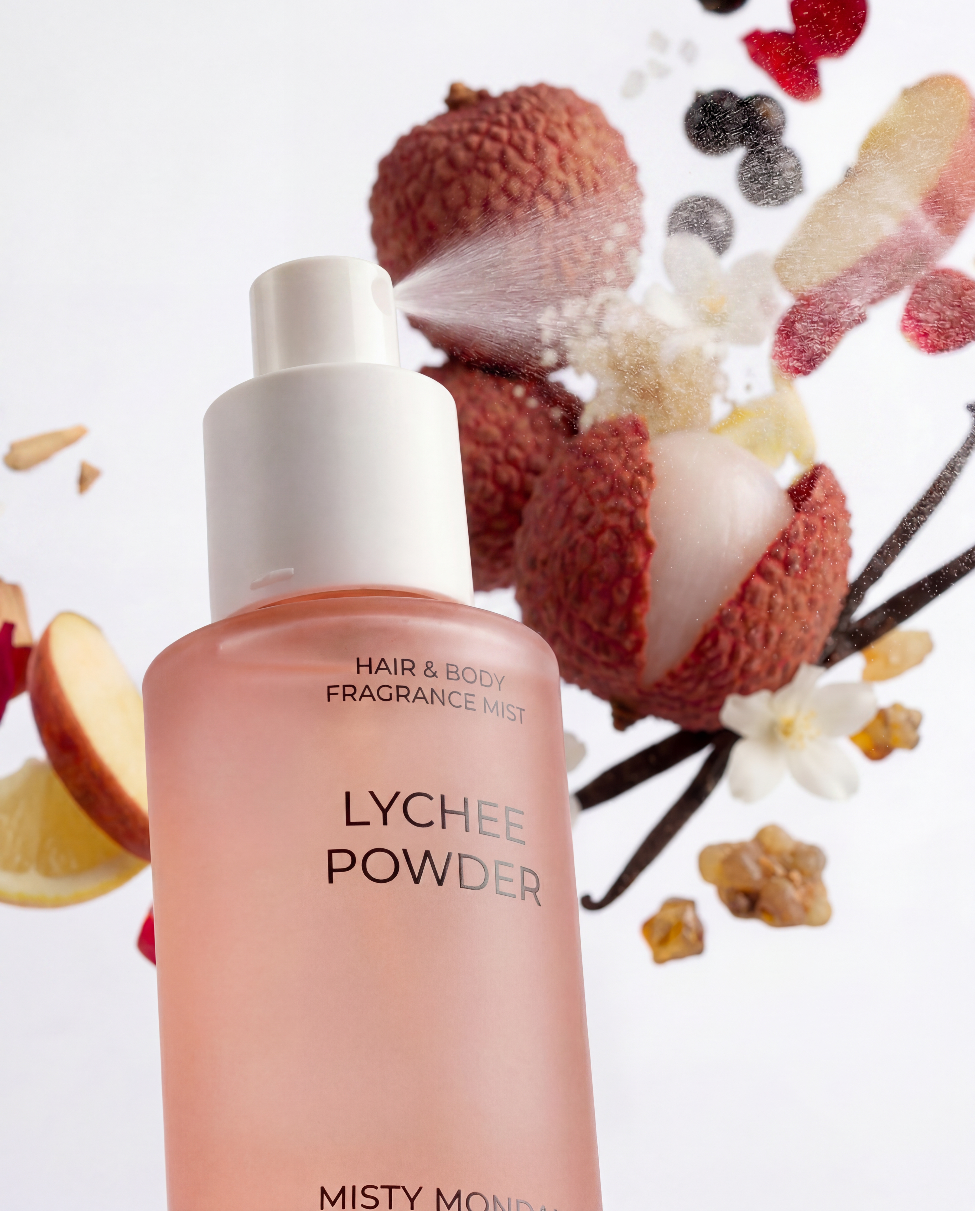 Misty Monday Lychee Powder haj- és testpermet permetez a háttérben virágokkal, gyümölcsökkel, vaníliarudakkal